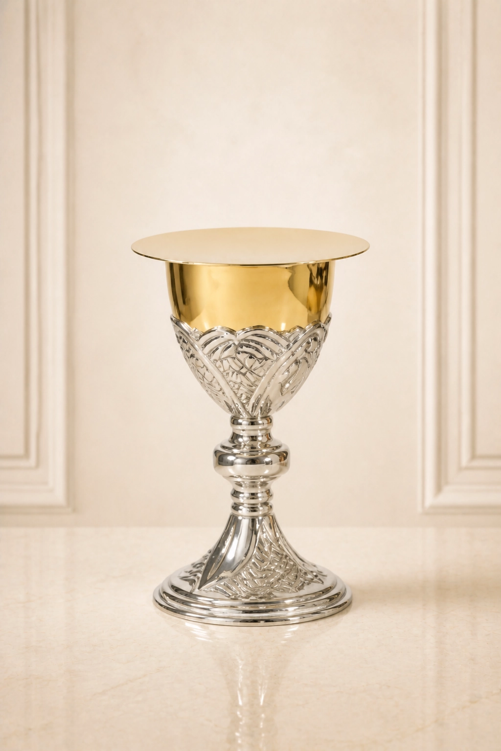 Cáliz litúrgico bicolor con patena circular, copa de borde dorado, relieve vegetal estilizado y base acampanada